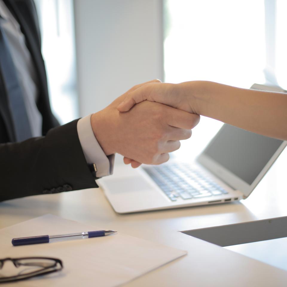 two people shaking hands over a desk